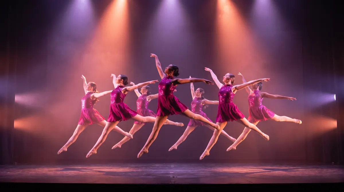 A competition dance team in matching costumes leaping on stage