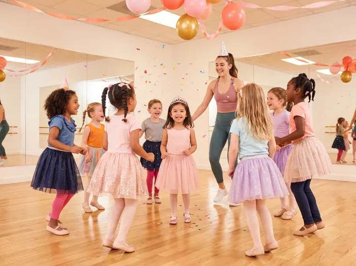 Children in tutus dancing at a birthday party with balloons and confetti