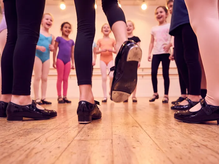 Children in tap shoes dancing on a wooden studio floor