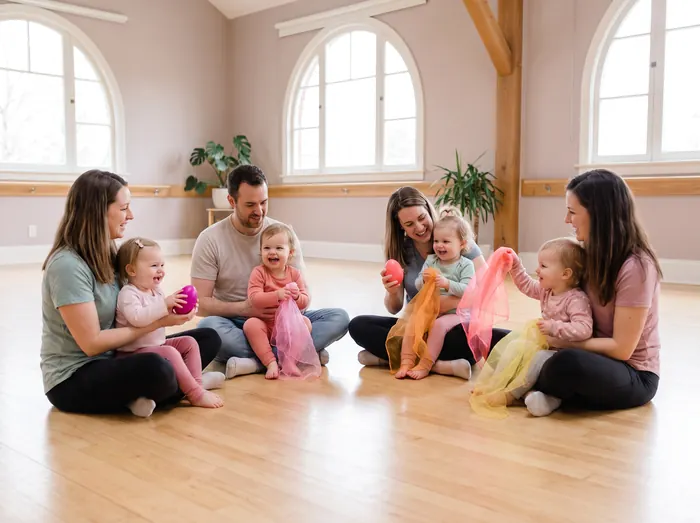 Parents and toddlers playing with scarves and shakers in a music and movement class
